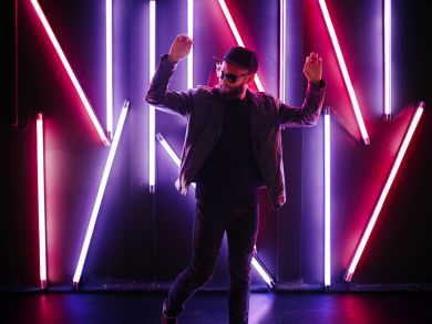 Ein tanzender Mann Ein Mann mit Sonnenbrille tanzt vor ein paar Neonröhren.