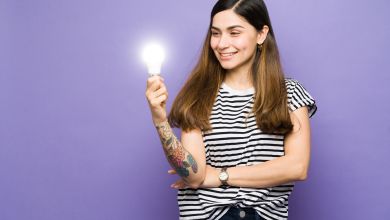 Frau mit Glühbirne Eine lächelnde Frau hält eine leuchtende Glühbirne in der Hand