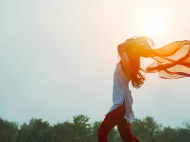 Eine Frau steht im Wind und ihr Schal weht mit dem Wind.