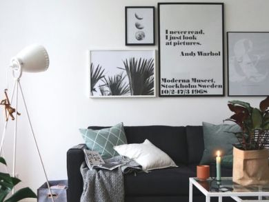 Sofa vor Bilderwand Schwarzes Sofa mit Kissen und Decke vor einer Bilderwand