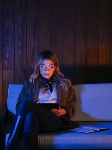 Frau mit Tablet Frau mit blonden langen Haaren sitzt entspannt auf der Couch und schaut auf ihr Tablet