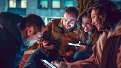 Vier Personen mit Smartphone Vier lächelnde Freundinnen und Freunde mit Smartphones in der Hand